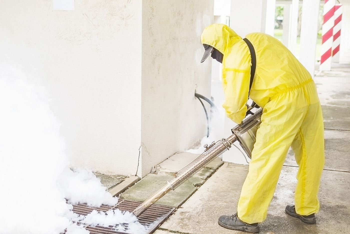 Technician in protective suit treating a drain area