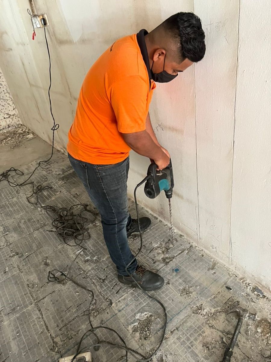 Technician drilling treatment points along an interior wall